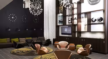 Modern lounge with brown leather chairs and patterned rugs. A wooden shelving unit displays books, globes, and a TV. Black wall features abstract clocks and art. Pendant lights hang from the ceiling, and a gray and green sofa completes the space.