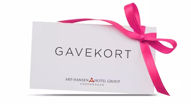 A gift card with GAVEKORT written in black, tied with a bright pink ribbon on the right side. The bottom text reads Arp-Hansen Hotel Group, Copenhagen with a red logo. The background is white.